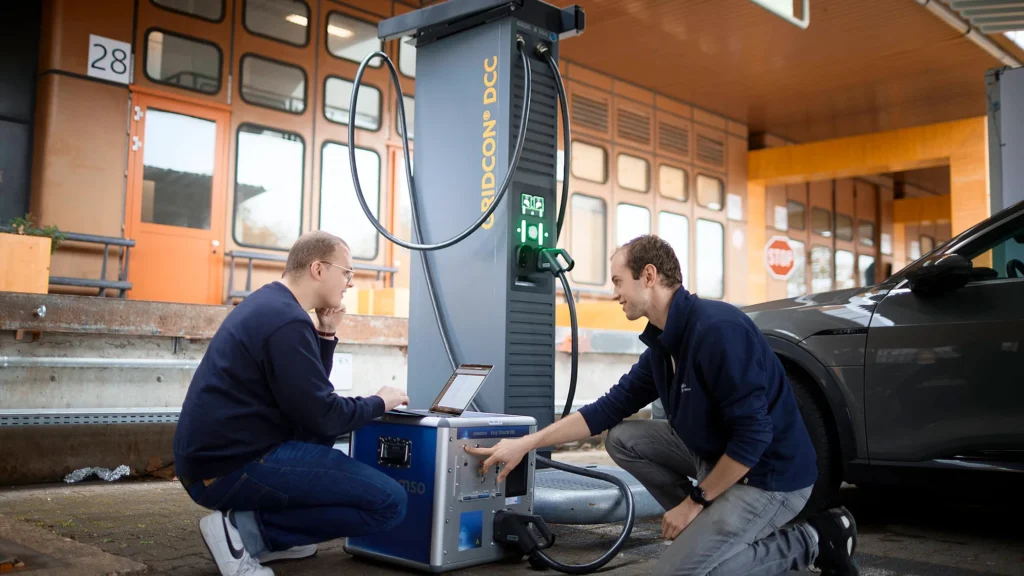 Zwei Mitarbeiter der Firma Reinhausen prüfen eine Schnellladesäule für E-Autos an einem Bestandsgebäude der Urban Tech Republic.